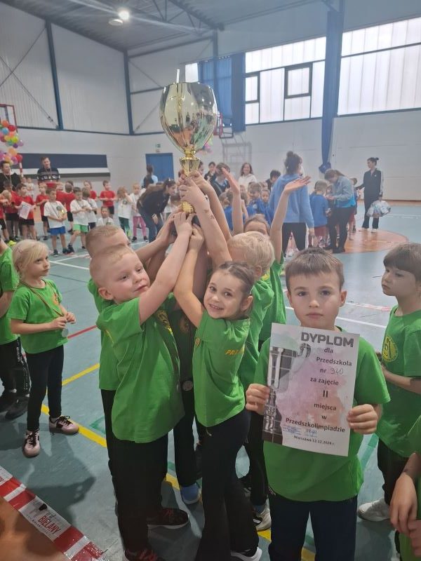 uśmiechnięte dzieci unoszace puchar zwycięstwa