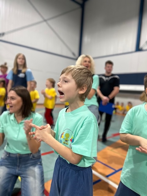 Chłopiec z grupy Turkusowej dopinguje kolegów i koleżanki podczas konkurencji.