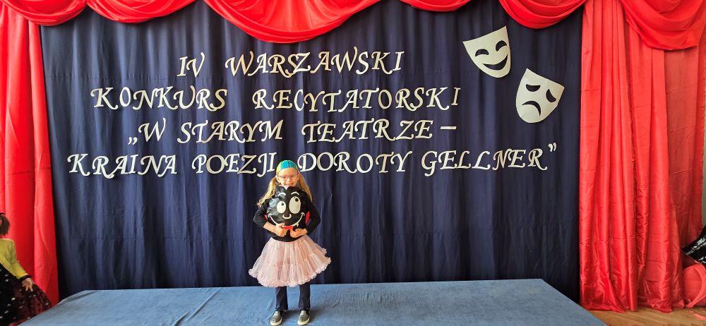 uśmiechnięta dziewczynka przebrana za piłkę stojąca na scenie