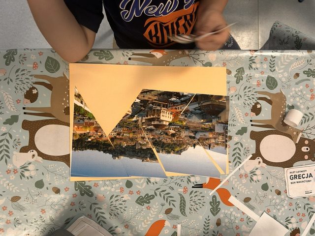 Dzieci z grupy niebieskiej podczas pracy w grupach układają puzzle z greckich miast.